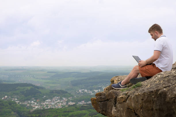 istock Handsome caucasian man with curly blond hair working at his notebook during hiking in mountains on background of beautiful view in Kislovodsk park. Distance work, outdoor office idea 1322088637