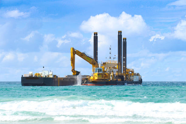 maquinaria pesada de dragado en el océano dragando arena justo al frente de la playa - draga fotografías e imágenes de stock