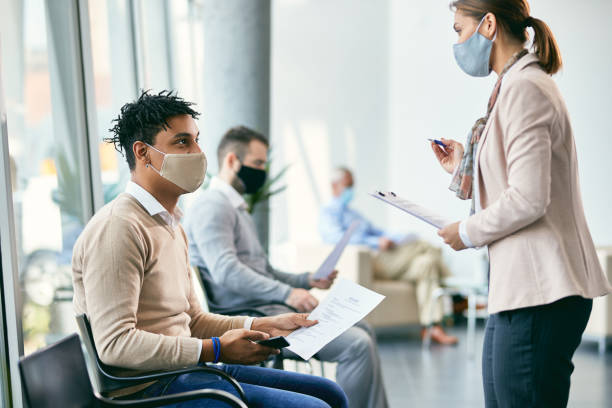 istock Young black candidate talking to human resource manager while waiting for job interview during COVID-19 pandemic. 1322088986