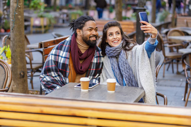 istock A Young Multi-Ethnic Couple is Spending a Wonderful Evening Together, Having a Lovely Communication and Sharing a Fresh Drink, and Taking Selfie Photos with Mobile Phone. 1322089686
