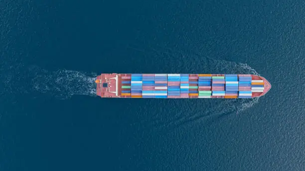 Aerial top view of a fully loaded container ship in the open sea.