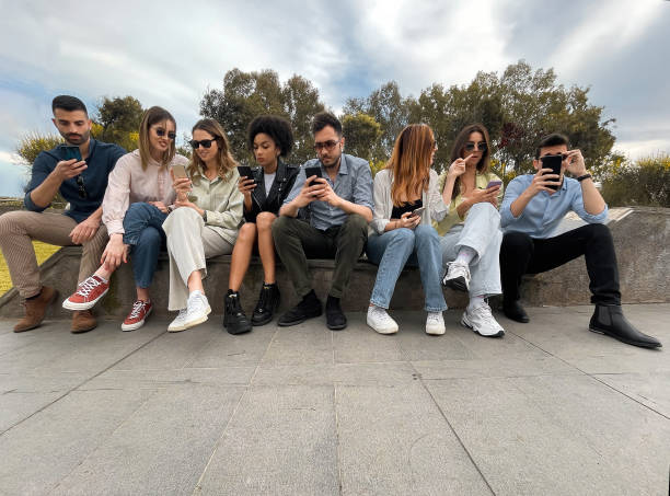 diversity young people browsing social network content online sitting on a bench in the park - family african ethnicity black african descent imagens e fotografias de stock