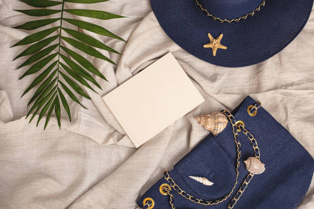 istock Summer background: blue straw hat, seashell bag, lettering book, palm leaf on textile linen background 1322096089