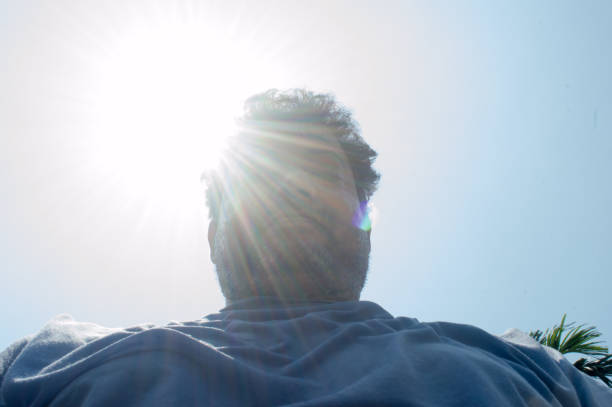 Scorching Hot summer sunlight rays falling human head. Man looks down on sun light heat temperature. Protection from ultraviolet light and sunburn background.  Sunstroke, heatstroke, greenhouse effect