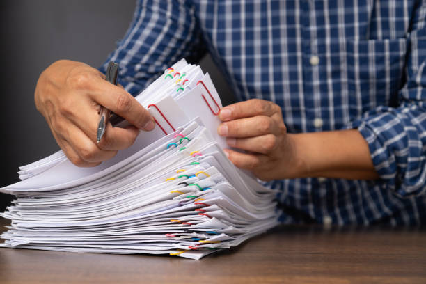 istock Close-up of man worker with white shirt holding stack of group report papers Document 1322098586