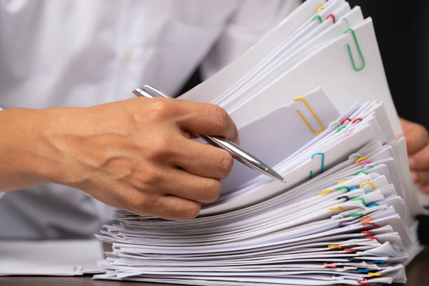 istock Close-up of man worker with white shirt holding stack of group report papers Document 1322098594