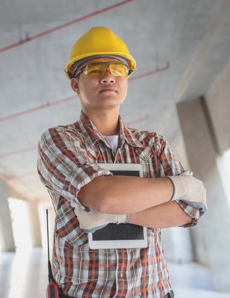 istock Portrait of Asian Construction engineer in hardhat holding digital tablet computer at construction site, Engineers at work checking construction building project on site 1322099754