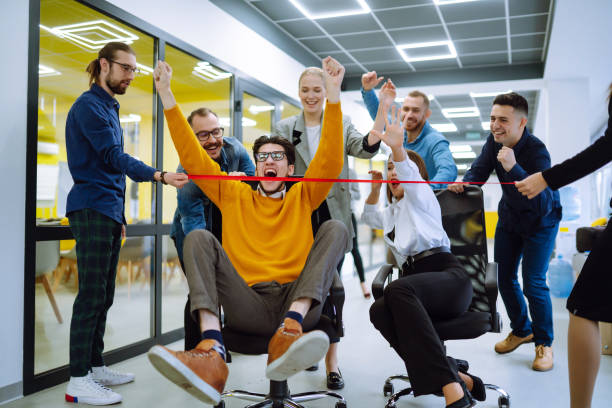 istock Young colleagues group having fun together, riding on chairs in office, diverse excited office workers enjoying break, laughing, engaged funny activity, celebrating corporate success. 1322099972
