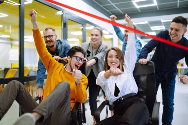 istock Young colleagues group having fun together, riding on chairs in office, diverse excited office workers enjoying break, laughing, engaged funny activity, celebrating corporate success. 1322100095