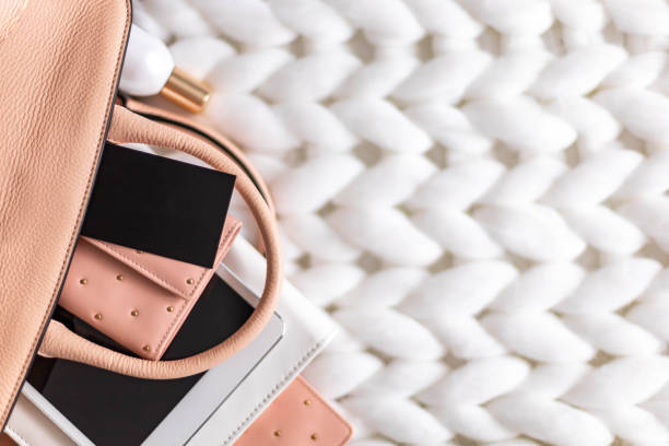 istock Top view composition organization storage of female handbag lying on white knitted plaid close up 1322103767