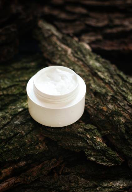 istock Cosmetic cream on tree bark. Organic cosmetology botanical concept. White plastic container with natural moisturizing balm. 1322104756