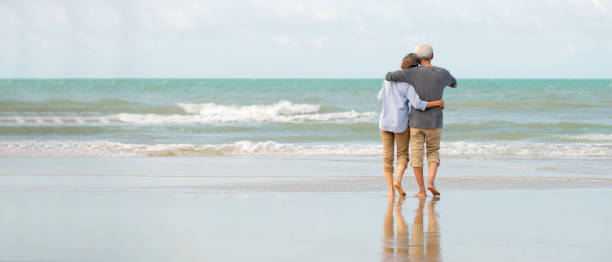 азиатские старшие пары пользуются на пляже - пенсия стоковые фото и изображения