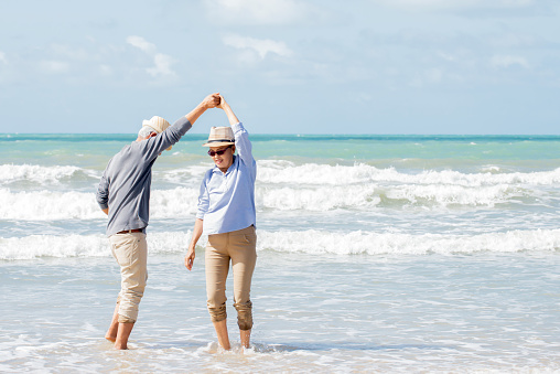 Happy asian couple dancing on the beach enjoy  life , Retirement  healthy lifestyle travel holiday summer concept