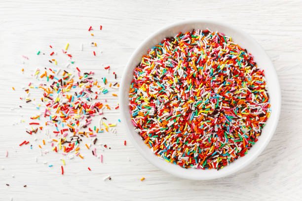 istock Multi colored Sugar sprinkle dots lie in a pile on a white plate, decoration for cake. 1322108874