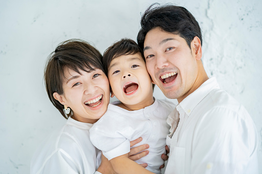 Parents and child lined up with a smile and a textured white background