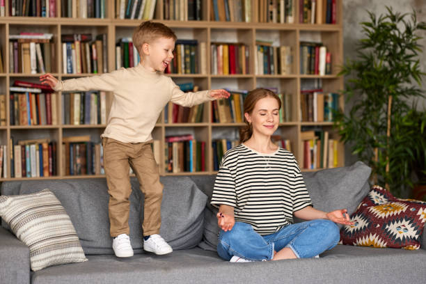 istock Young mother meditating with closed eyes while her son jumping o 1322113218