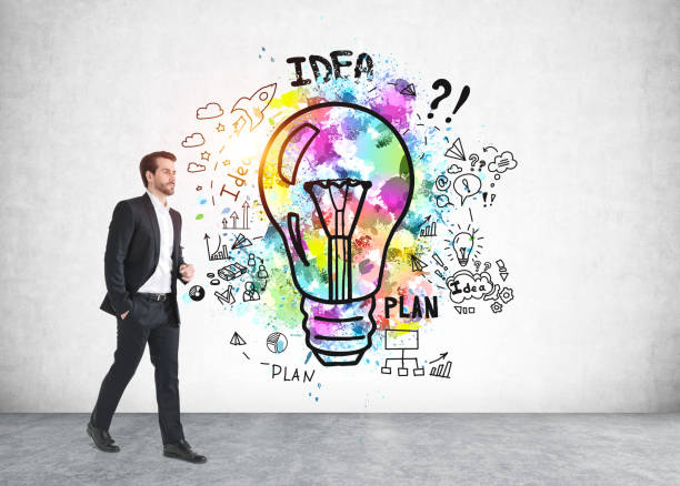 istock Businessman walking in concrete room, light bulb on a grey wall 1322115389
