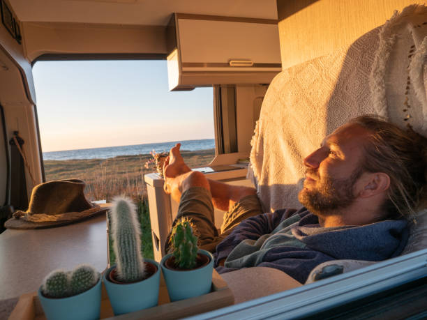istock Man lying in a van looking at ocean 1322116445