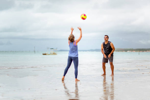 couple jouant au volley-ball sur la plage - beach volleying ball playing photos et images de collection
