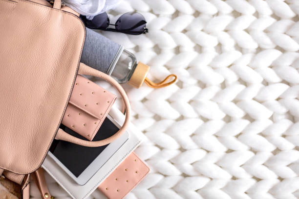 istock Top view composition organization storage of female handbag lying on white knitted plaid close up 1322123818