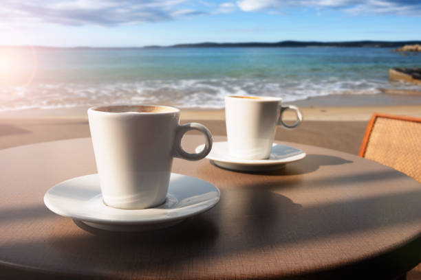 Two cups of coffee on a table at the beach. Atmospheric mediterranean vacation photography with a beautiful sea view.
