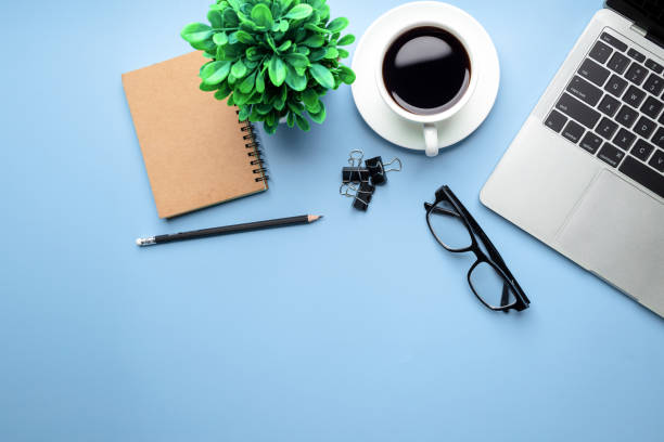 istock Flat lay, top view office table desk. Workspace with, laptop,office supplies, pencil, green leaf, and coffee cup on blue background. 1322135448