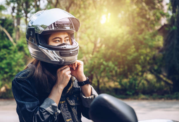 Confidence Asian woman wearing a motorcycle helmet before riding. Helmets contribute to motorcycle safety by protecting the rider's head. biker stock pictures, royalty-free photos & images