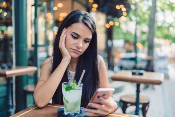 Depressed woman drinking mojito Thoughtful woman at sidewalk cafe drinking cold cocktails waiting telephone on the phone frustration stock pictures, royalty-free photos & images