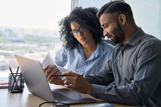istock Multiethnic mentor and intern employees doing paperwork together in office. 1322139112
