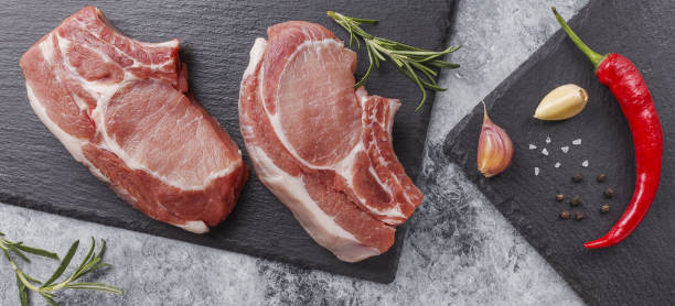 istock Raw pork steak on a dark background with herbs. 1322140152