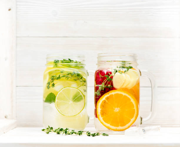 istock Summer cold lemonade with oranges, limes, ginger and currant berries in a glass jar on a white wooden background 1322142006