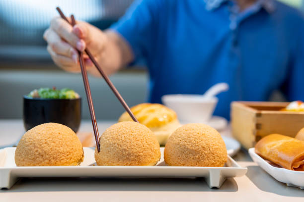 uomo che mangia guangdong dim sum con le bacchette nel ristorante - human hand baked food pineapple foto e immagini stock