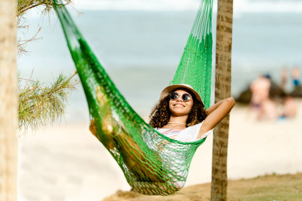 istock Young woman relaxing in a hammock at beach 1322142793
