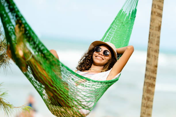 young woman relaxing in a hammock at beach - hammock beach vacations tropical climate imagens e fotografias de stock