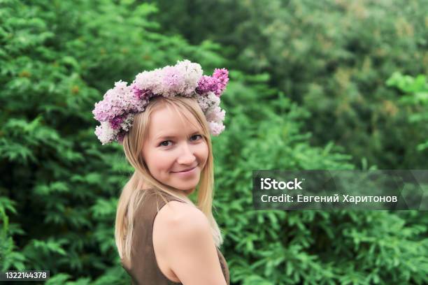 Young Woman In A Floral Wreath Of Lilac Flowers On A Natural Background Outdoors Stock Photo - Download Image Now