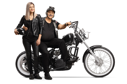 Mature biker and a young woman in leather clothes standing next to his chopper isolated on white background