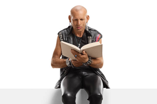 homem punk sentado em um painel e lendo um livro - men reading outdoors book - fotografias e filmes do acervo