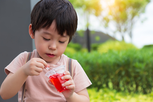 Cute little child love eating sweets or snack. Handsome little boy enjoy eating gelatin or jelly. Adorable kid like eating snack. He feel happy when he eat favorite sweet with garden background