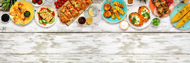istock Summer BBQ grill top border over a white wood banner background. Overhead view with copy space. 1322149882