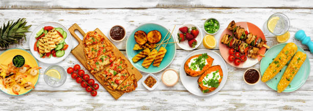 istock Summer BBQ grill table scene over a white wood banner background. Overhead view. 1322151279