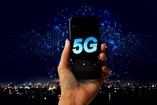 Holograma digital de red 5G e internet de las cosas en el fondo de la ciudad - Concepto de teléfono móvil de mano de la tecnología futura Red 5G photo