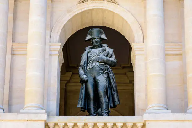 Low angle view of the statue of Napoleon Bonaparte by french sculptor Charles Emile Seurre on the balcony of the southern facade of the court of honor of the Hotel des Invalides in Paris, France.