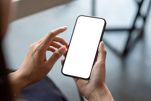 Primer plano de la mano de un hombre de negocios que sostiene una pantalla blanca del teléfono inteligente está en blanco, el fondo está borroso. maqueta. photo