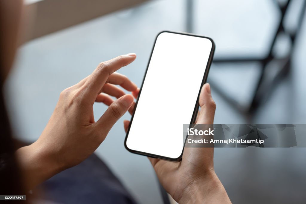 Close-up of a businessman hand holding a smartphone white screen is blank the background is blurred.Mockup. Mobile Phone Stock Photo