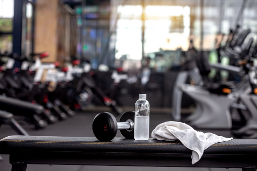 Mancuerna, botella de agua, toalla en el banco en el gimnasio. photo