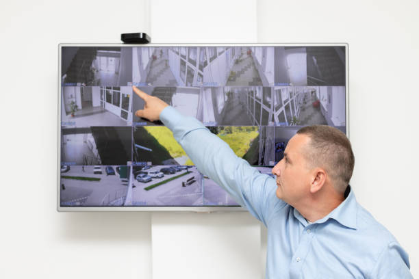 istock security guard standing in front of large CCTV monitor 1322158135