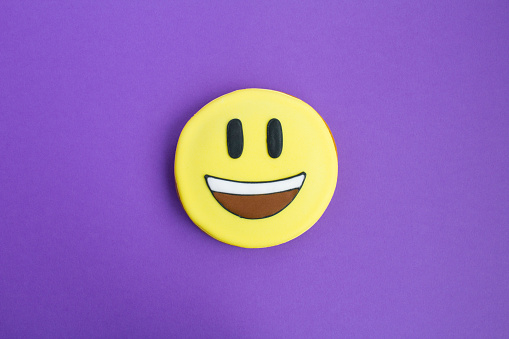 Smiley in the form of gingerbread on the purple background. Top view. Close-up. Copy space.