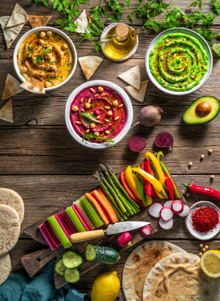 istock Hummus Three bowl of chickpeas, avocado and beetroot with cut vegetables for dip on rustic wood table 1322160069