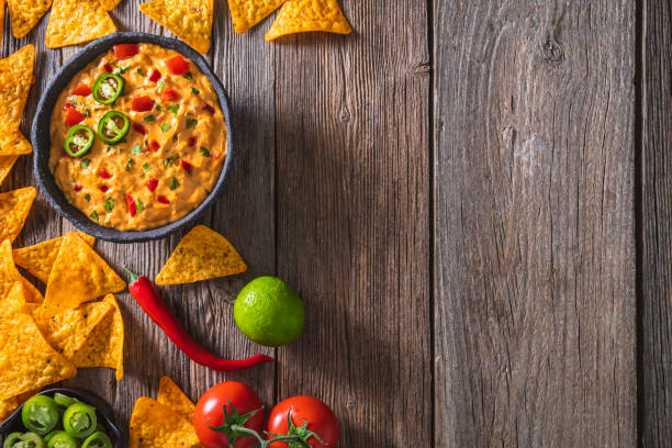 istock cheedar cheese dip sauce with Nacho chips with tomato and chili on a rustic wooden table 1322160141