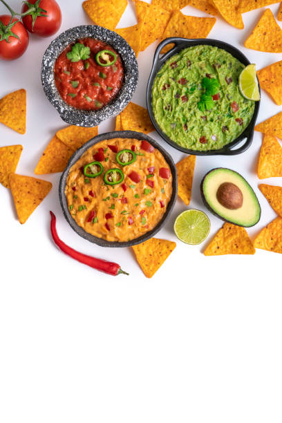istock Mexican dip sauces guacamole, cheedar dip and tomato salsa with Nacho chips isolated on white 1322160199